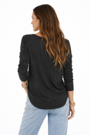 Woman wearing a black long-sleeve top and light blue jeans on a white background