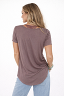 Woman wearing a mauve t-shirt and light blue jeans on a white background
